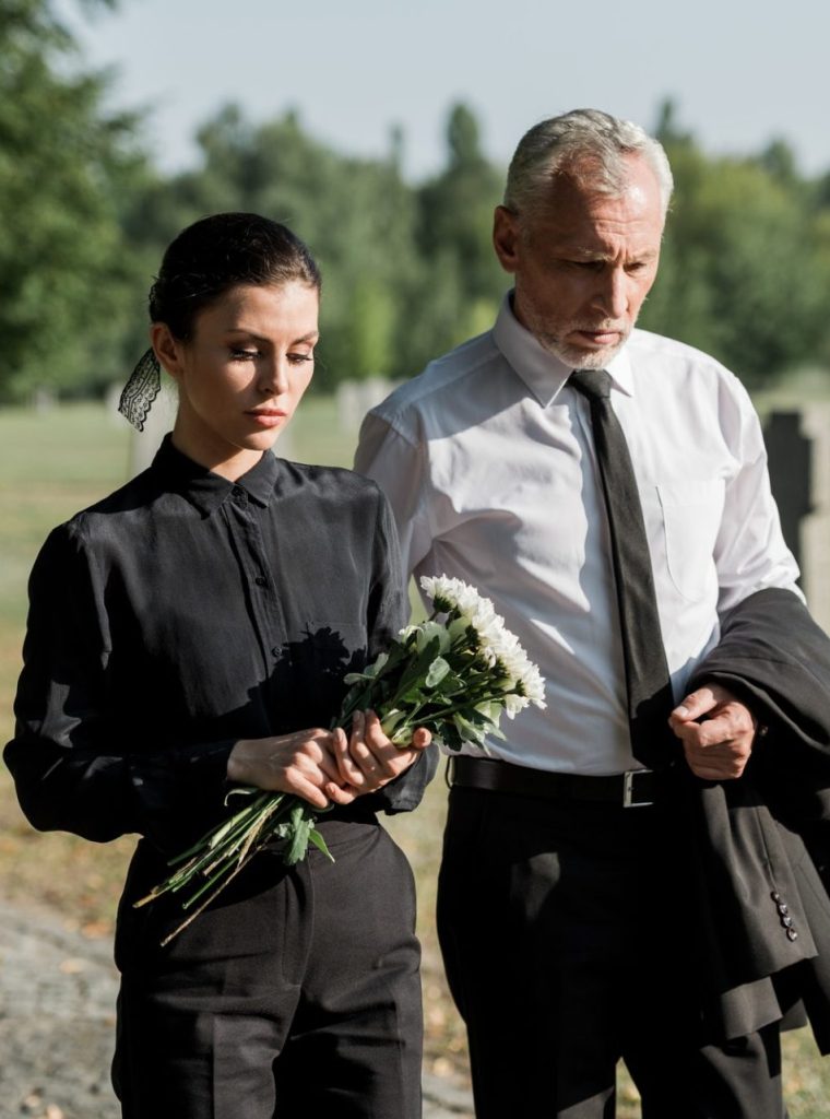 bearded-senior-man-walking-near-woman-with-flowers-on-funeral-e1636904705190.jpg